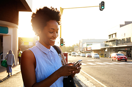 Digital Marketing Agency in Pittsburgh - woman standing at a crosswalk looking at her cell phone.