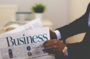 Business section of the newspaper is held by two hands