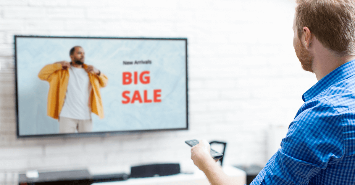 Man sitting and watching TV commercial that says "BIG SALE"