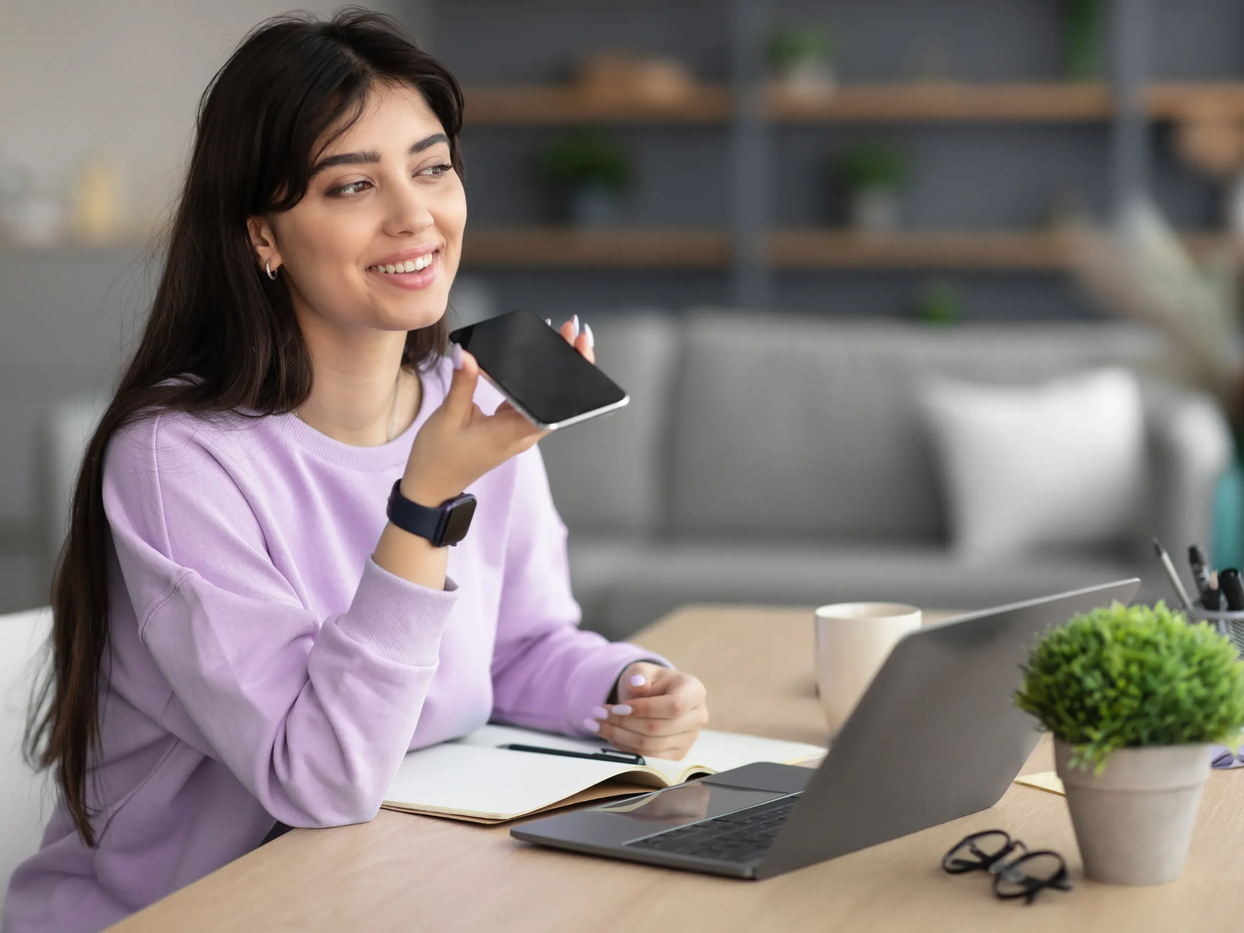woman speaking in a phone in front of her laptop