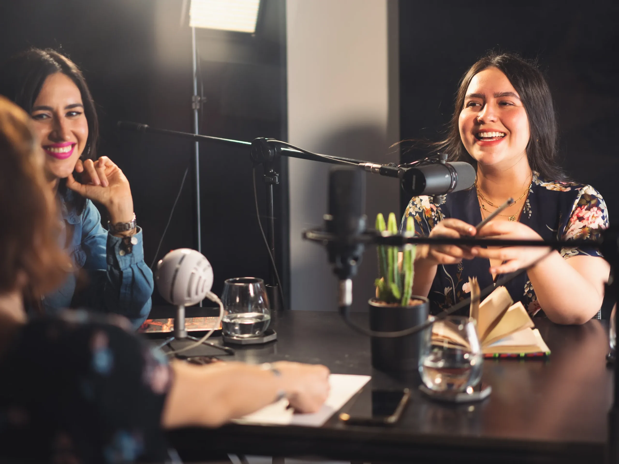 group of women laughing while recording a podcast