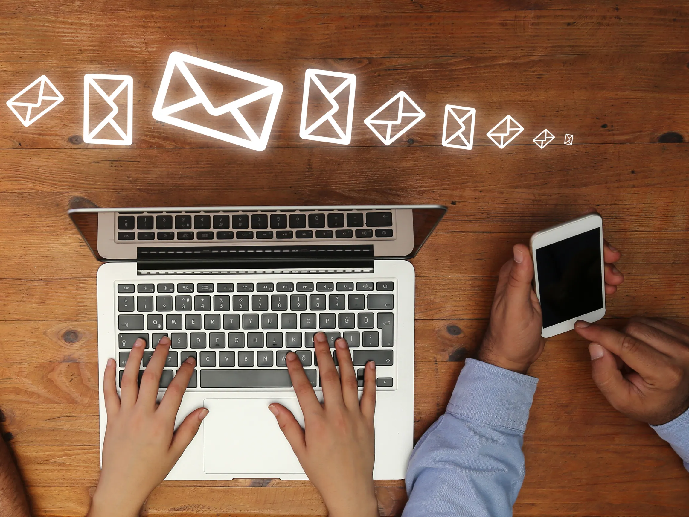 person using laptop and person using phone with hovering mail icons - representing email marketing strategies
